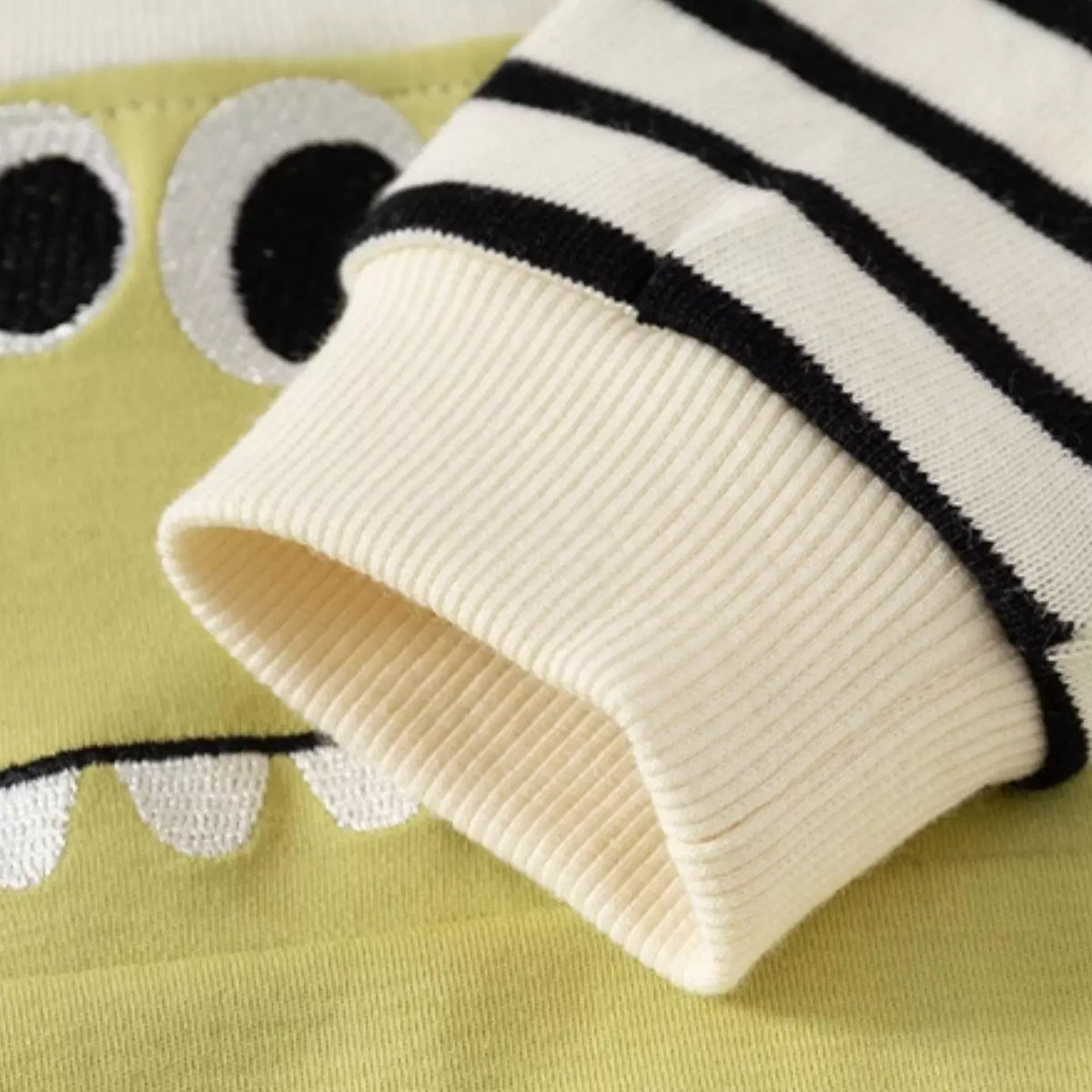 Ribbed cream cuff and stripe sleeve detail on the dinosaur romper