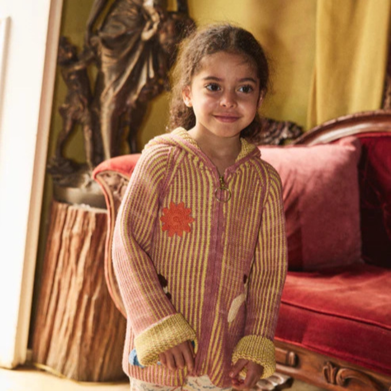 Smiling girl in a rose knit hoodie cardigan indoors