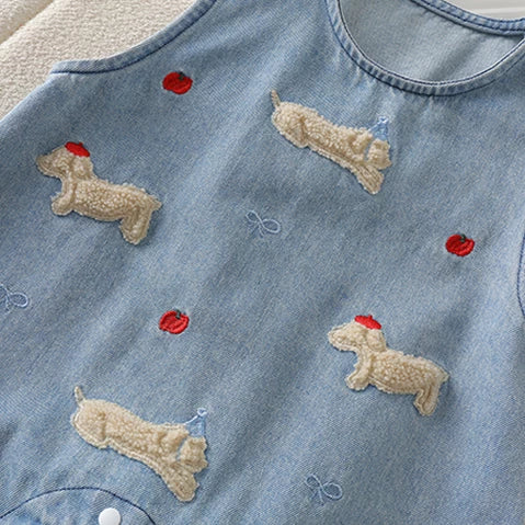 Close-up of textured dachshund appliqués and red embroidered apples on denim