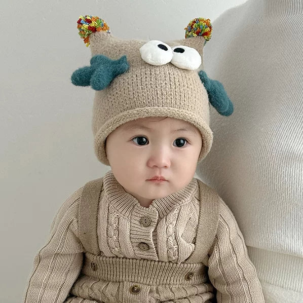Baby wearing an oatmeal knit beanie with googly eyes and pom-pom ears