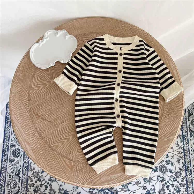 Ink black stripe button-front baby romper, flat lay on a wooden tray