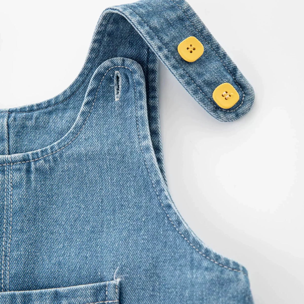 Close-up of adjustable denim strap with two yellow buttons