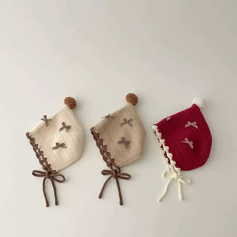 Cream, oat and berry red knit pixie bonnets with bows, flat lay
