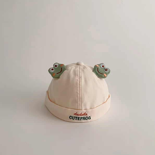 Cream baby beanie with two frog faces and a rolled brim