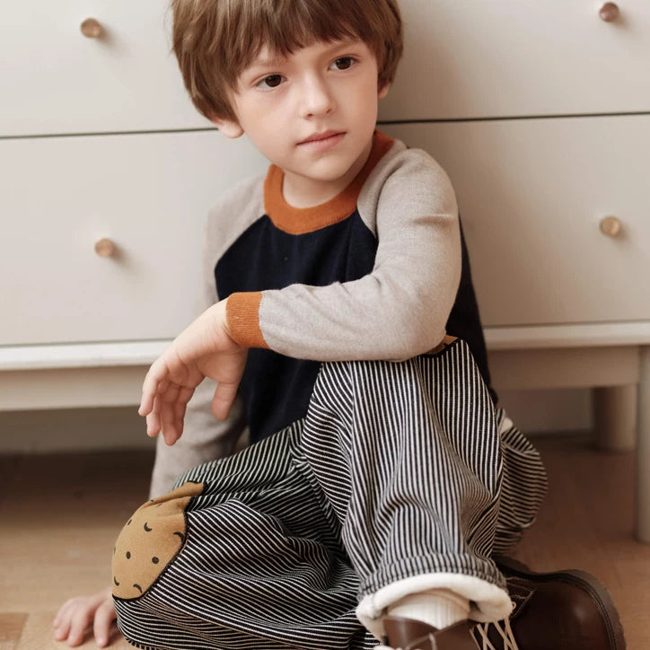 Child sitting cross-legged in fleece-lined striped pants