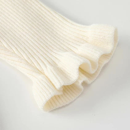 Close-up of ruffled ribbed cuff on cream girls top
