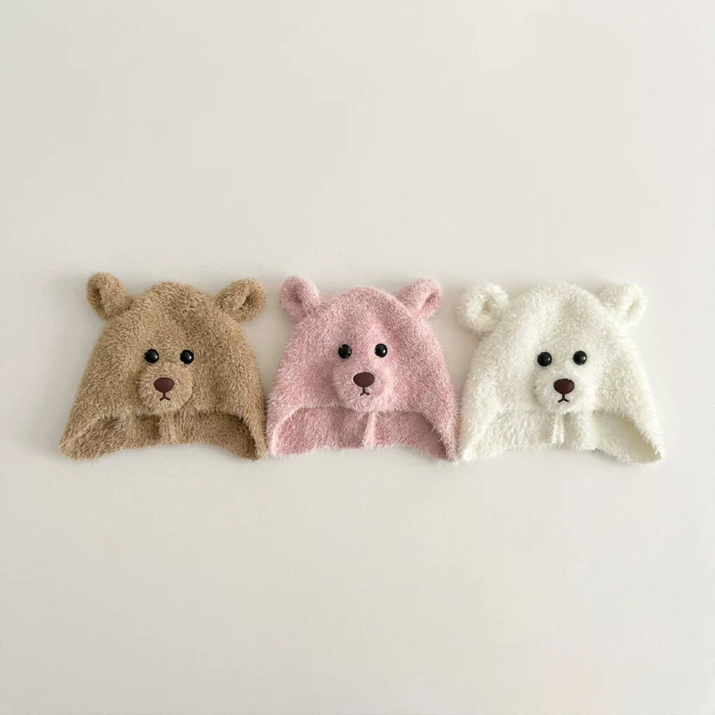 Three fluffy bear ear-flap hats in latte, rose and cream, flat lay