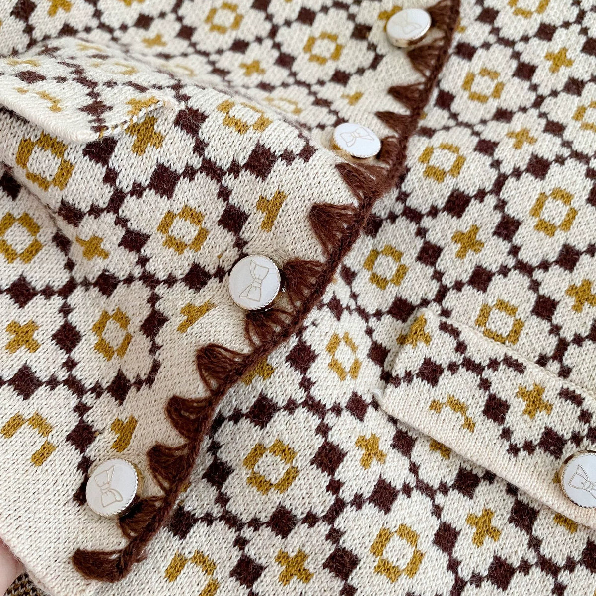 Close-up of the cardigan knit pattern, scalloped trim and buttons