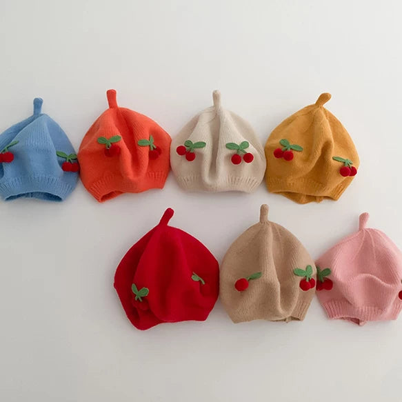 Seven baby cherry berets in all colours, flat lay