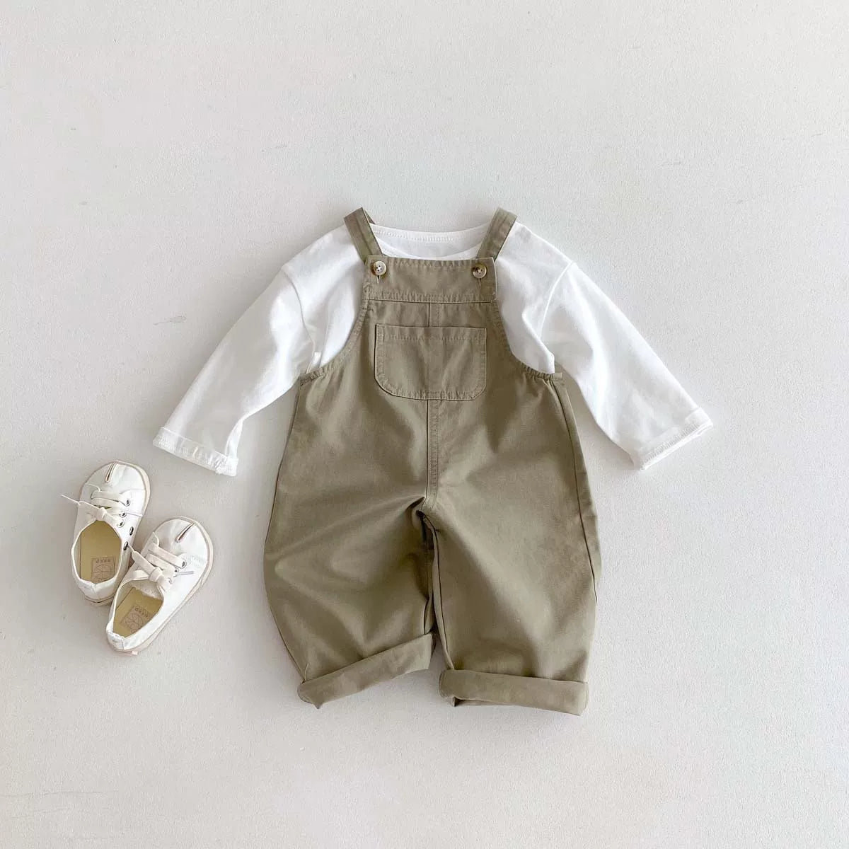 Khaki overalls styled with a white tee and canvas sneakers