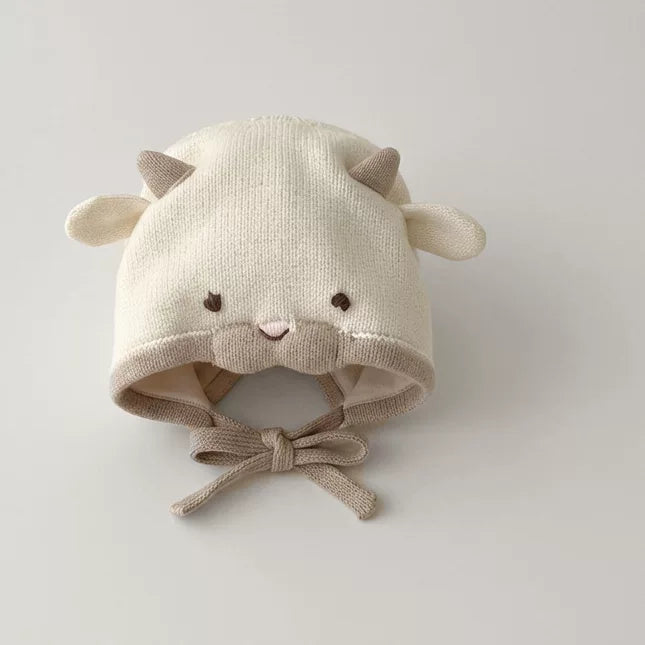 Cream knit lamb baby bonnet with tan ears and chin ties, flat lay