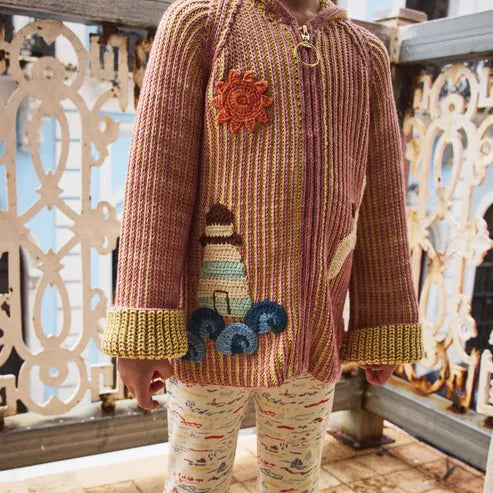 Child wearing a rose zip-up knit cardigan on a balcony