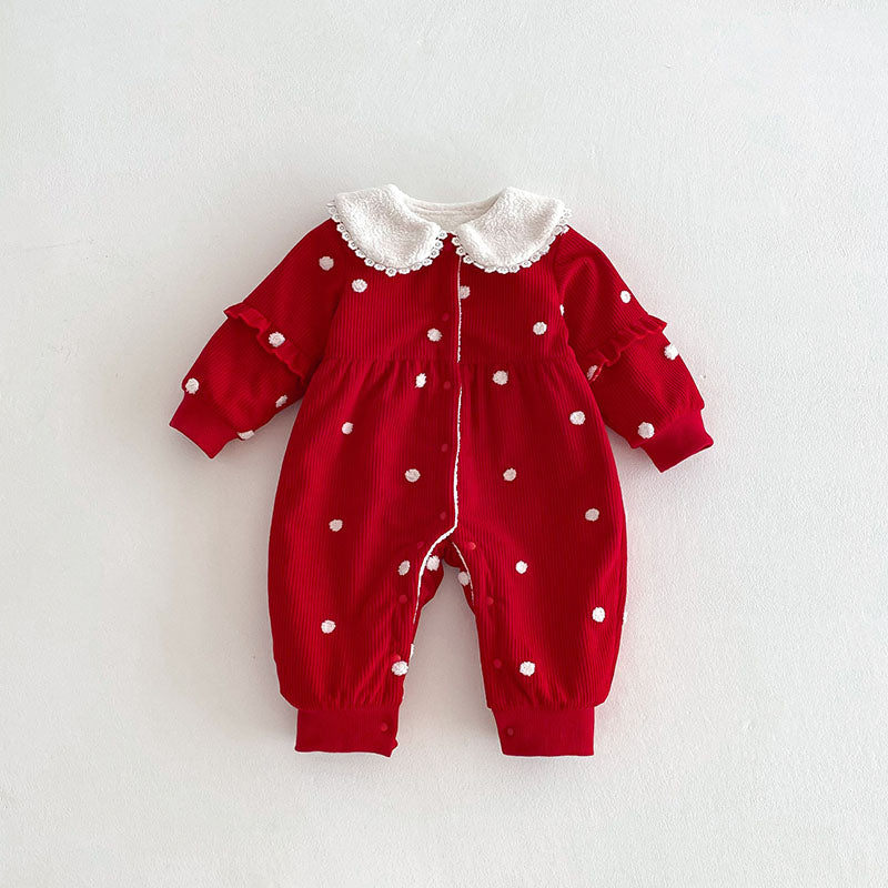 A charming red baby jumpsuit with white polka dots, ruffle details on the sleeves, and a delicate white faux fur collar edged with lace. The jumpsuit is displayed against a clean white background, showcasing its vibrant color and soft texture