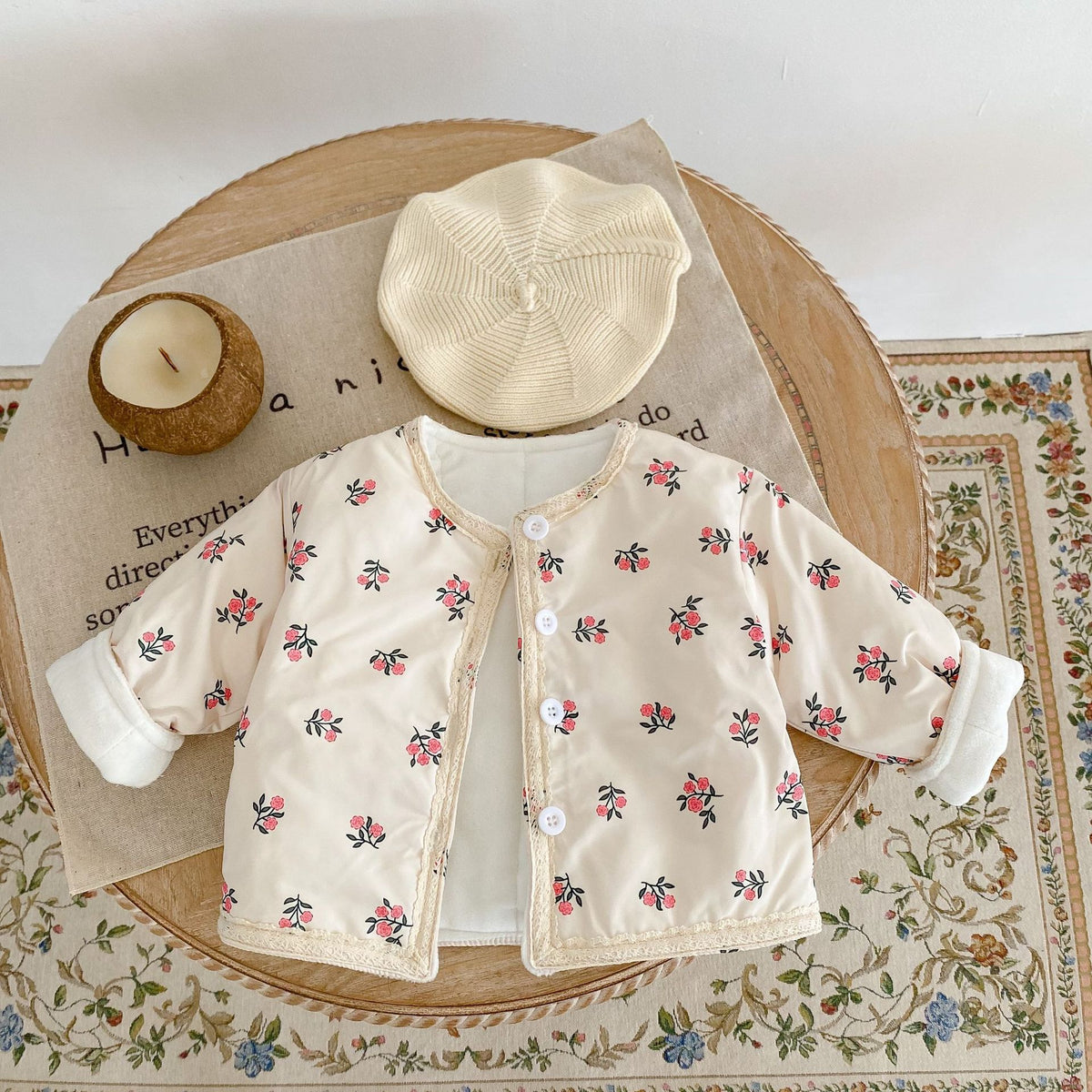 Apricot floral jacket with beret on a rug