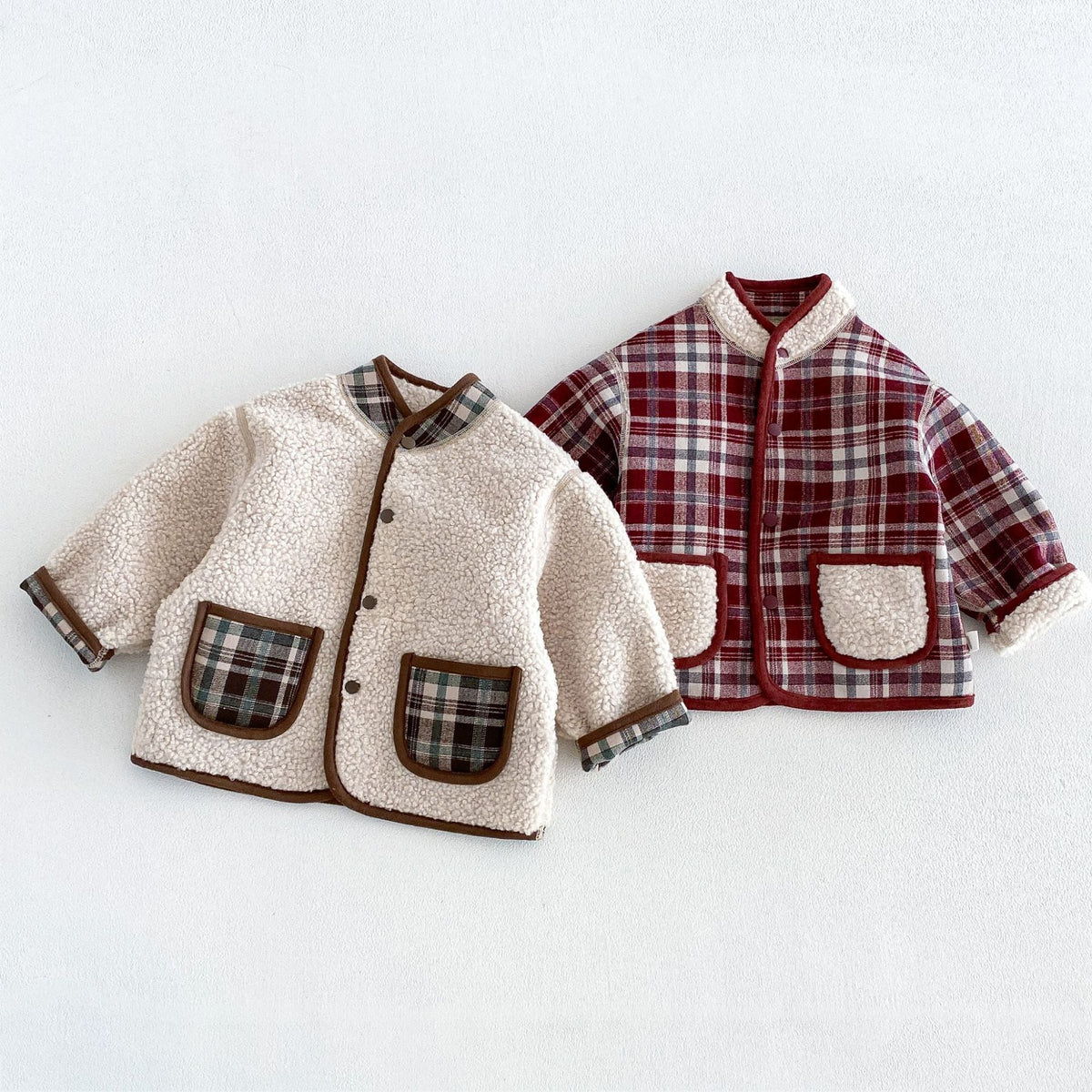 Reversible toddler jackets in cream sherpa and berry plaid, flat lay