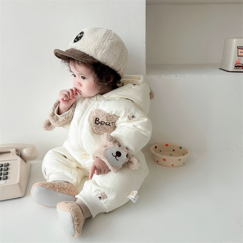 Baby sitting in cream bear snowsuit and hat