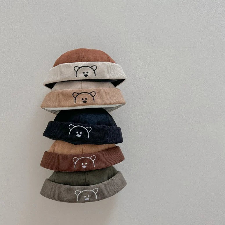 Stack of bear embroidered corduroy baby hats in five colours