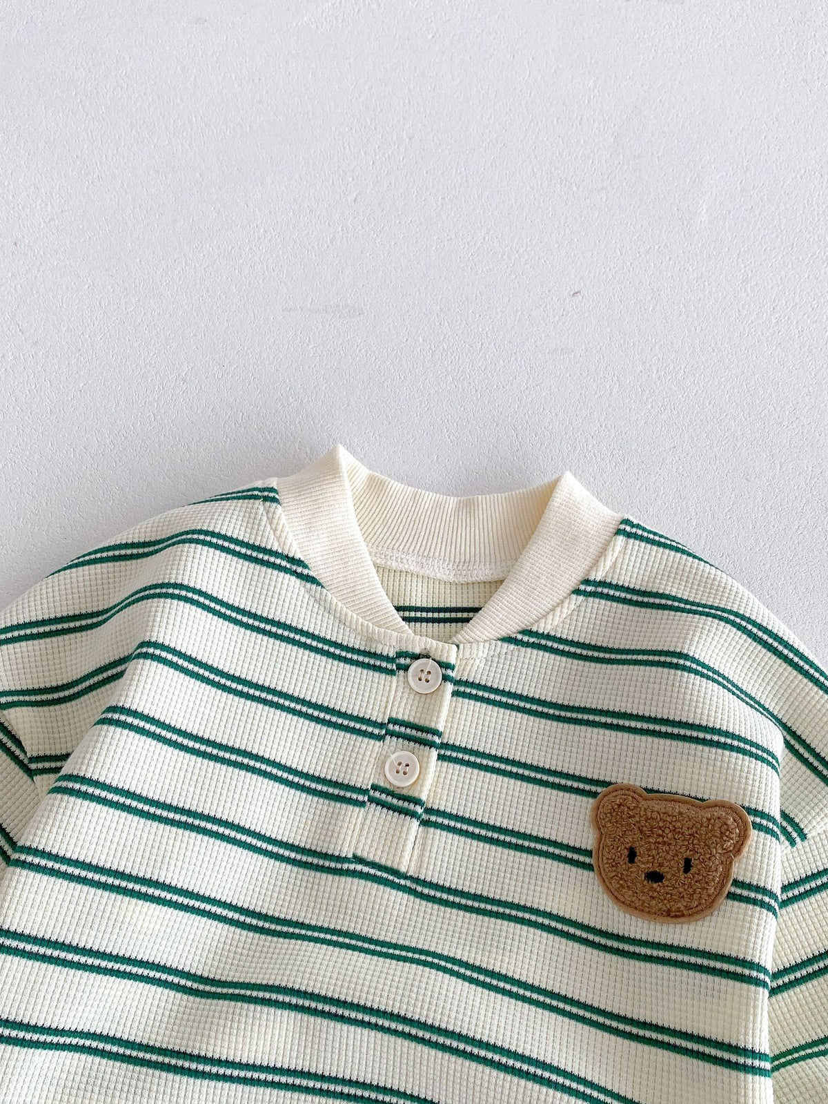 Close-up of teddy bear patch on striped sweatshirt