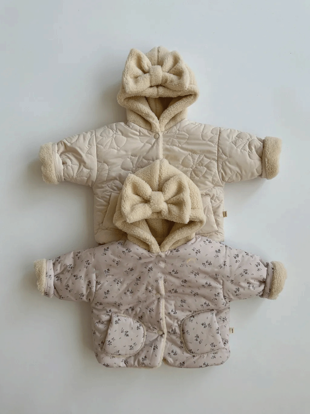 Beige and floral bow hood baby jackets stacked