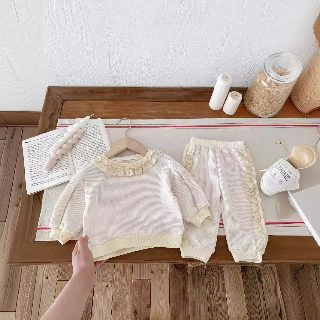 Beige knit sweater and joggers with frill trim on hangers