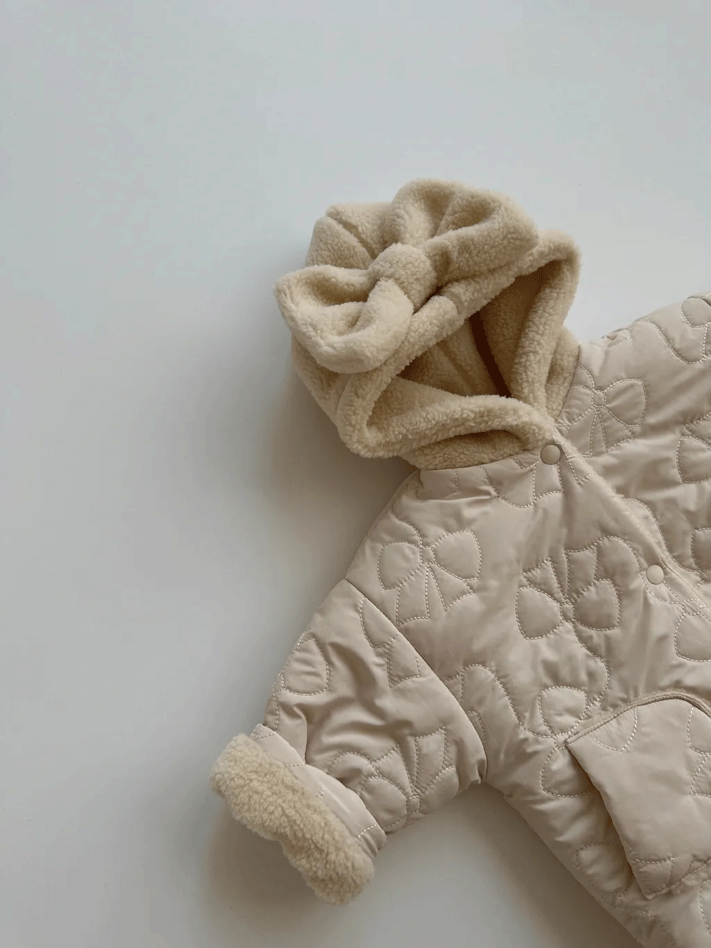 Side view of beige quilted bow jacket