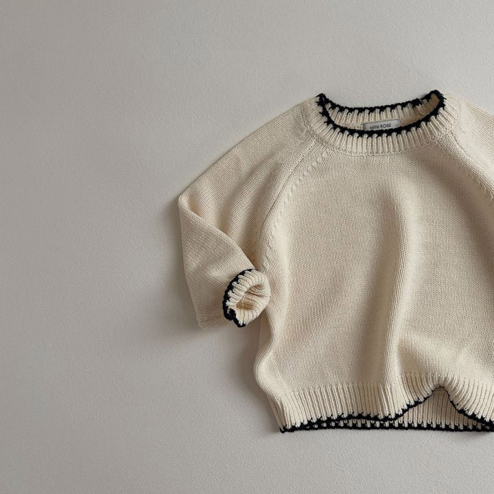 Close-up of beige knit sweater with black trim