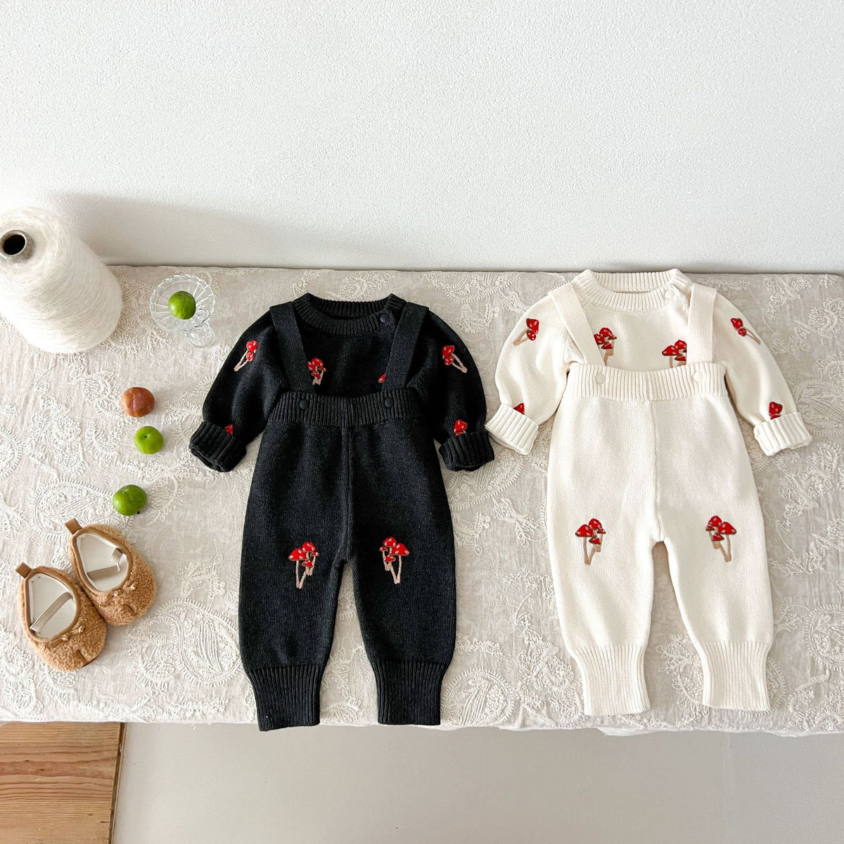 Black and cream mushroom knit sweater and suspender pants sets laid flat