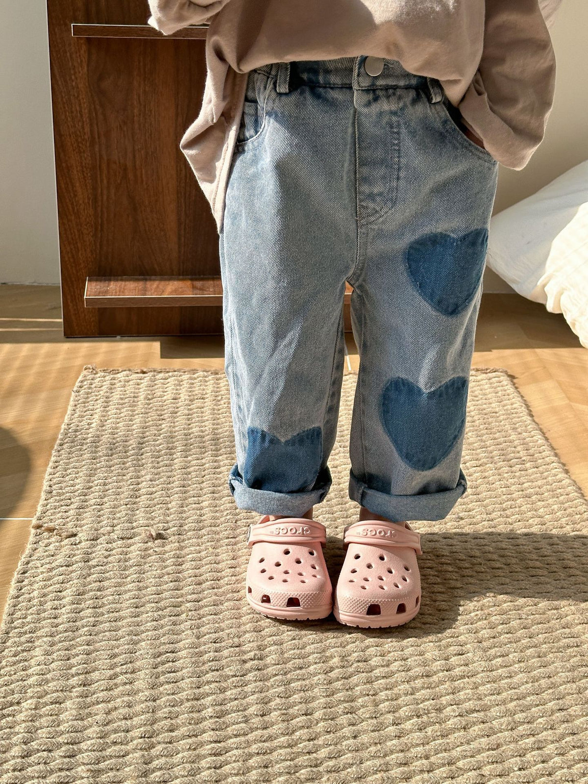 Toddler wearing blue heart patch jeans with pink clogs