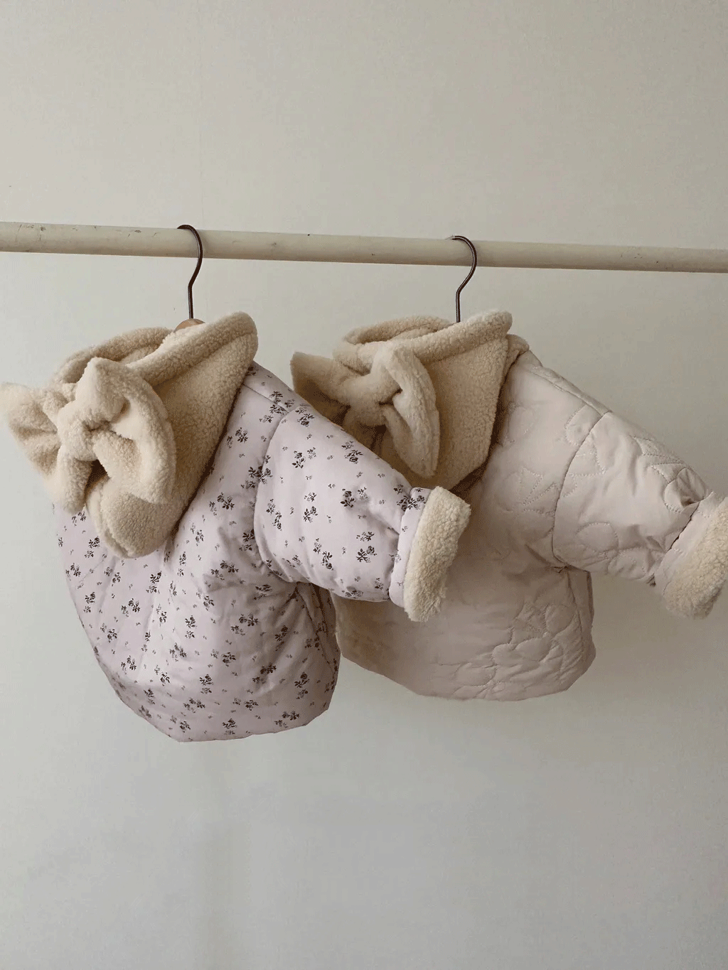Floral and beige bow hood jackets hanging on hangers