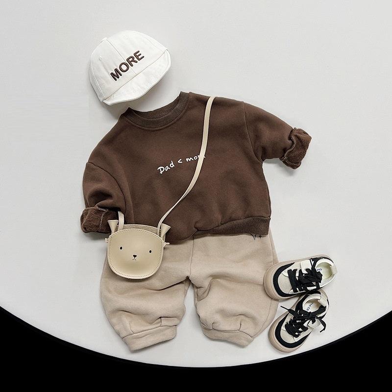 Brown Dad < Mom sweatshirt styled with beige trousers and cap