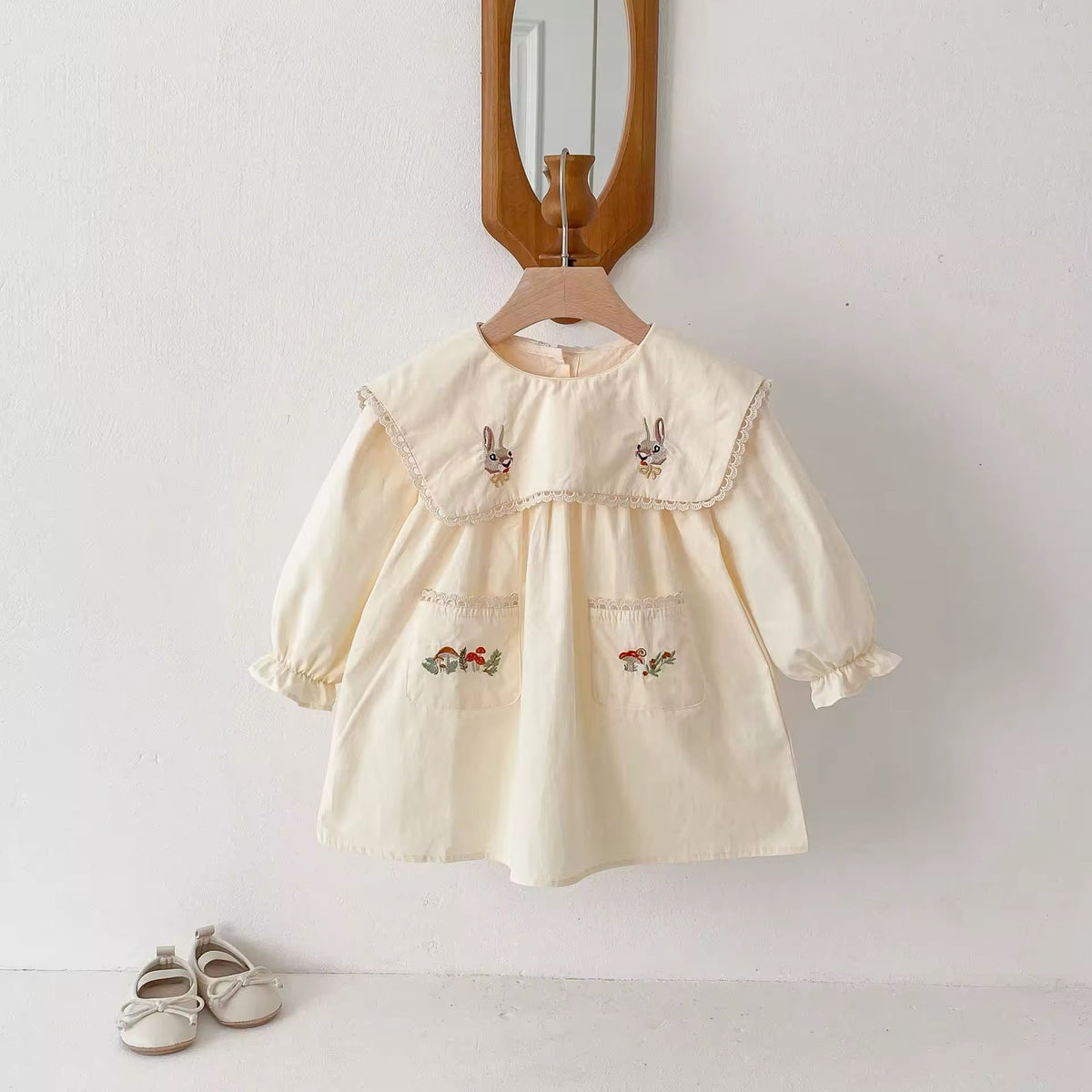 Cream girls dress with bunny embroidered sailor collar on a hanger