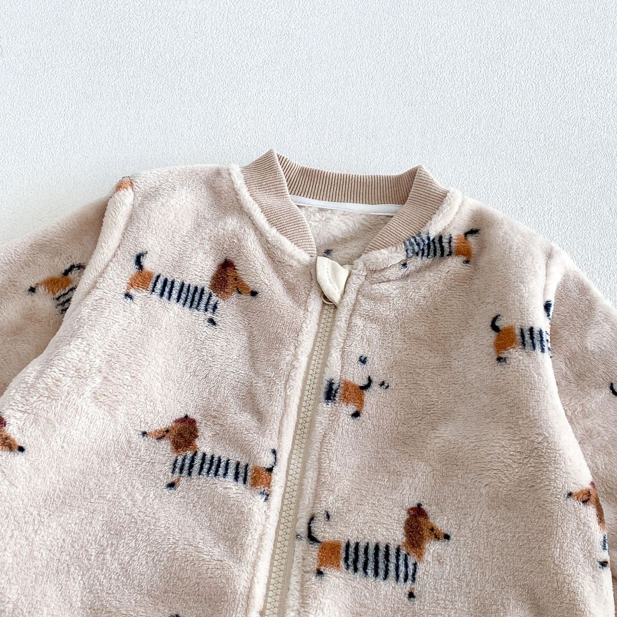 Close-up of the ribbed collar and zip guard on the plush romper