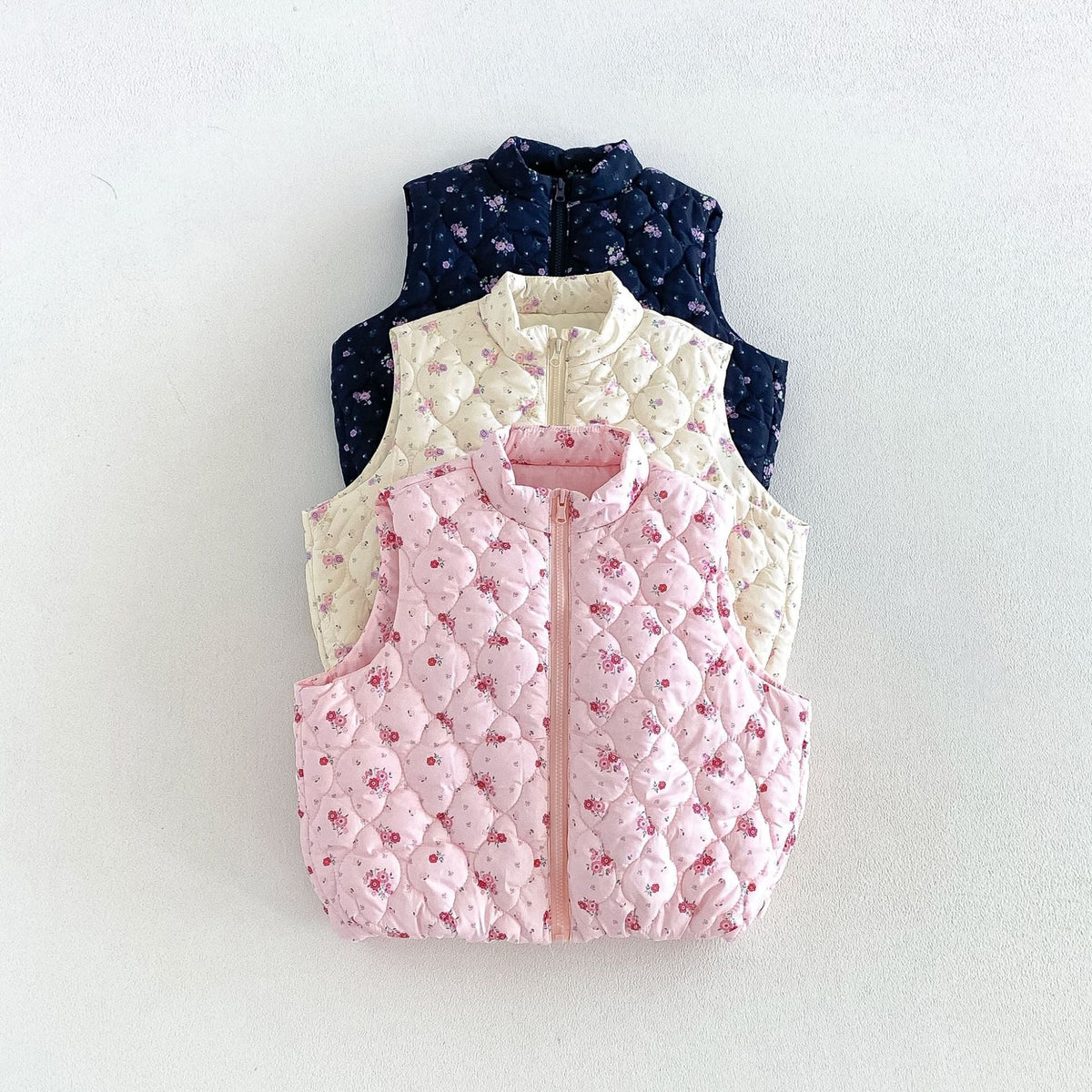 Navy, cream and pink floral puffer vests stacked