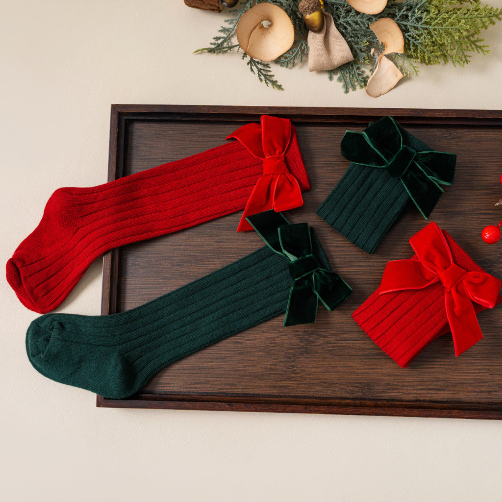 Red and green Christmas bow socks on a wooden tray