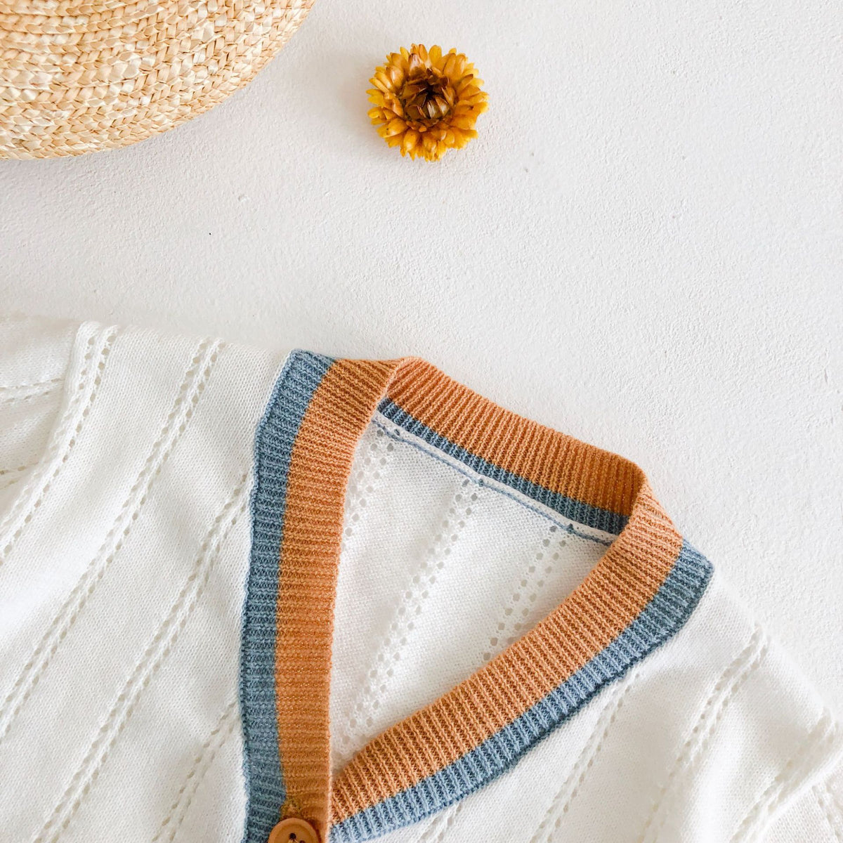 Close-up of orange and blue trim on white cardigan