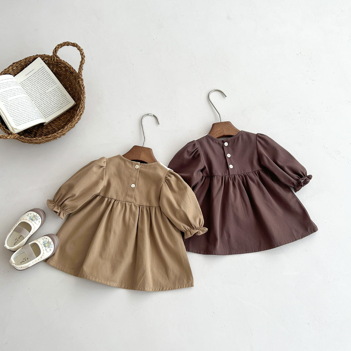 Two corduroy dresses on hangers laid flat