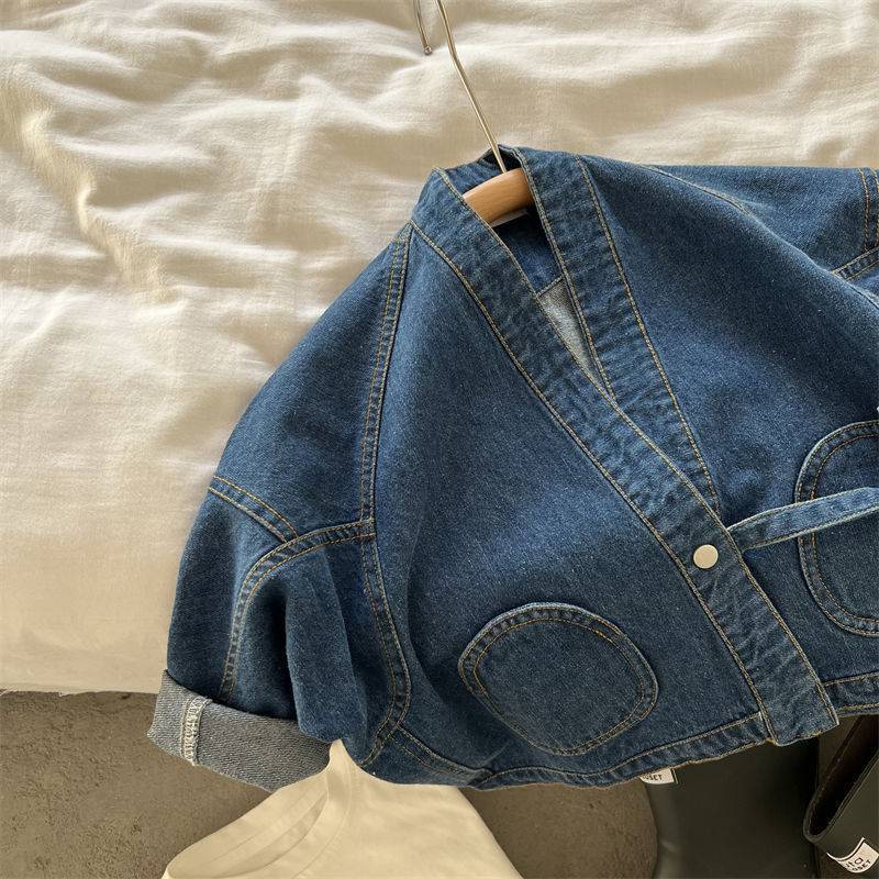 Blue denim jacket on a hanger with elbow patch