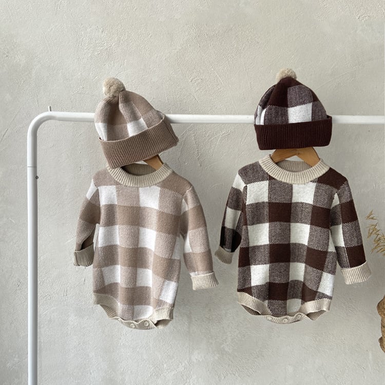 Two gingham knit baby rompers on hangers