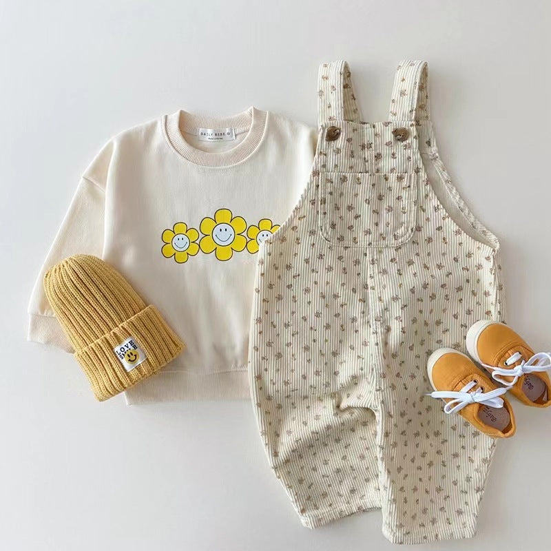 Floral print baby overalls styled with cream sweatshirt and yellow beanie