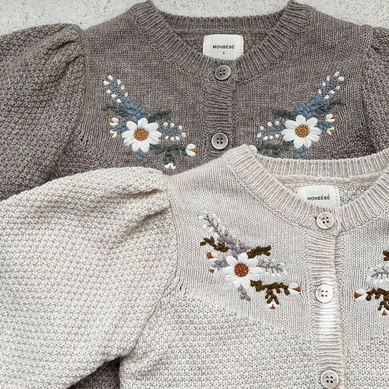 Close-up of floral embroidery on grey and apricot cardigans