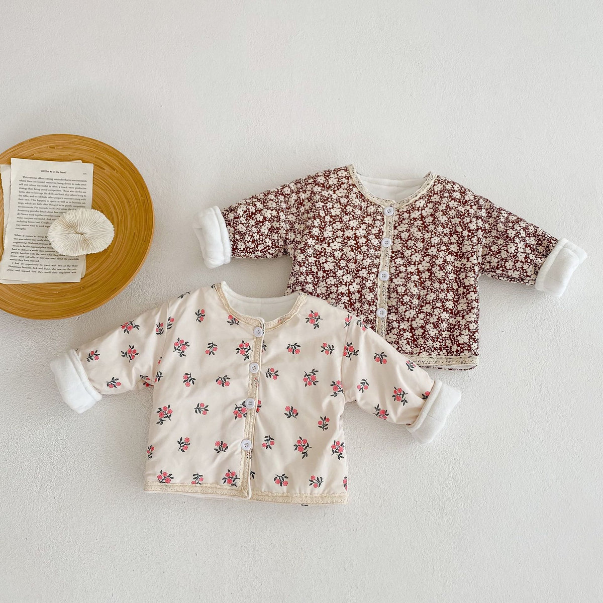 Two floral padded baby jackets laid flat
