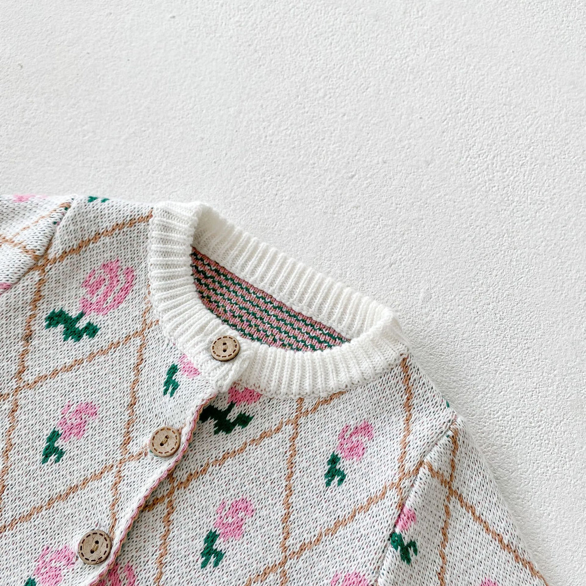 Close-up of neckline and wooden buttons on floral knit baby cardigan