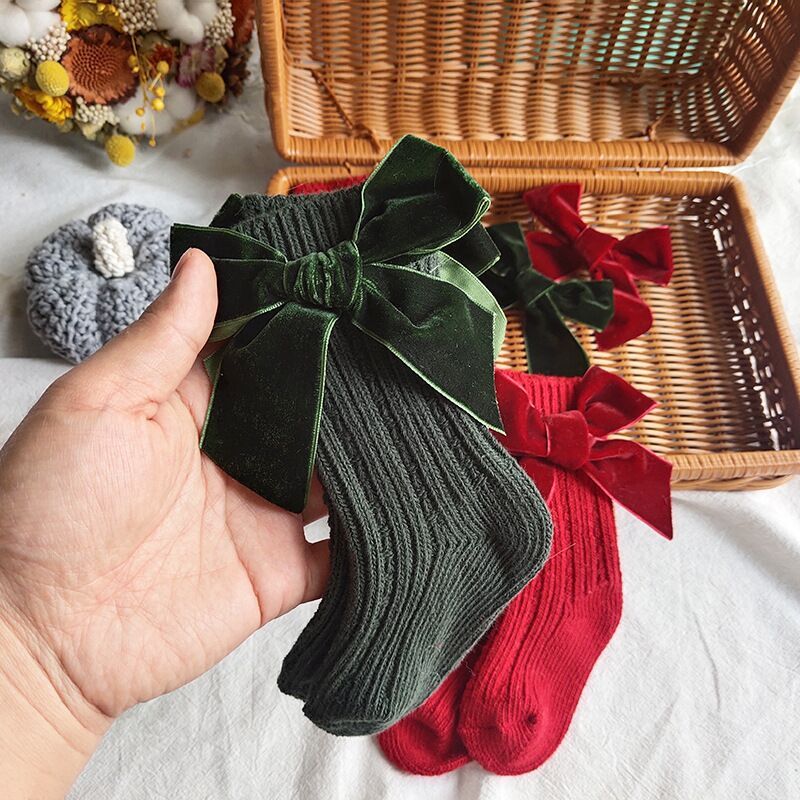 Dark green and red velvet bow knee socks held in hand