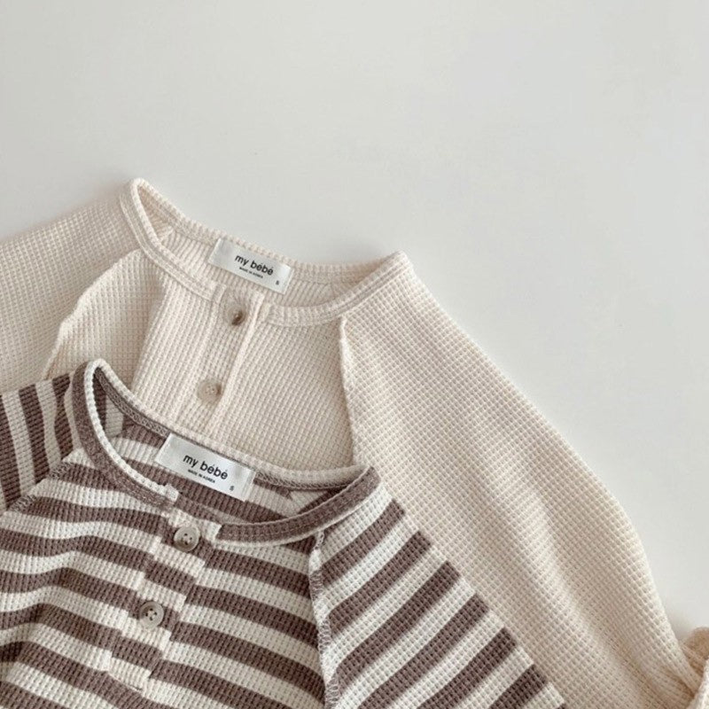 Close-up of henley button placket on beige and striped tops