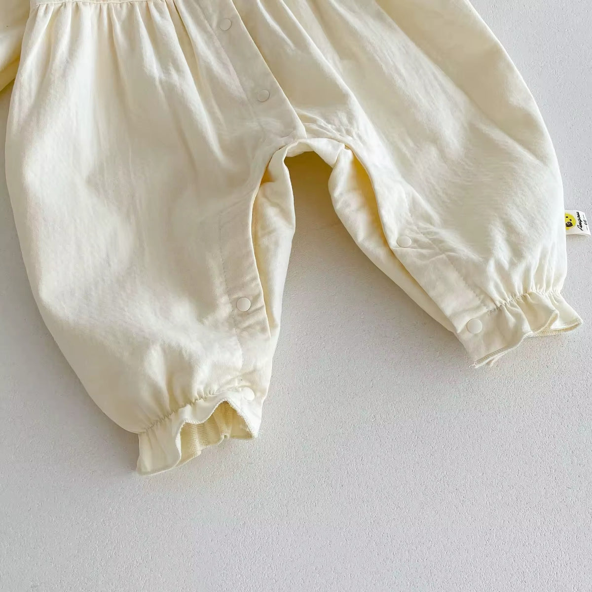 Elastic ankle cuffs on cream baby jumpsuit