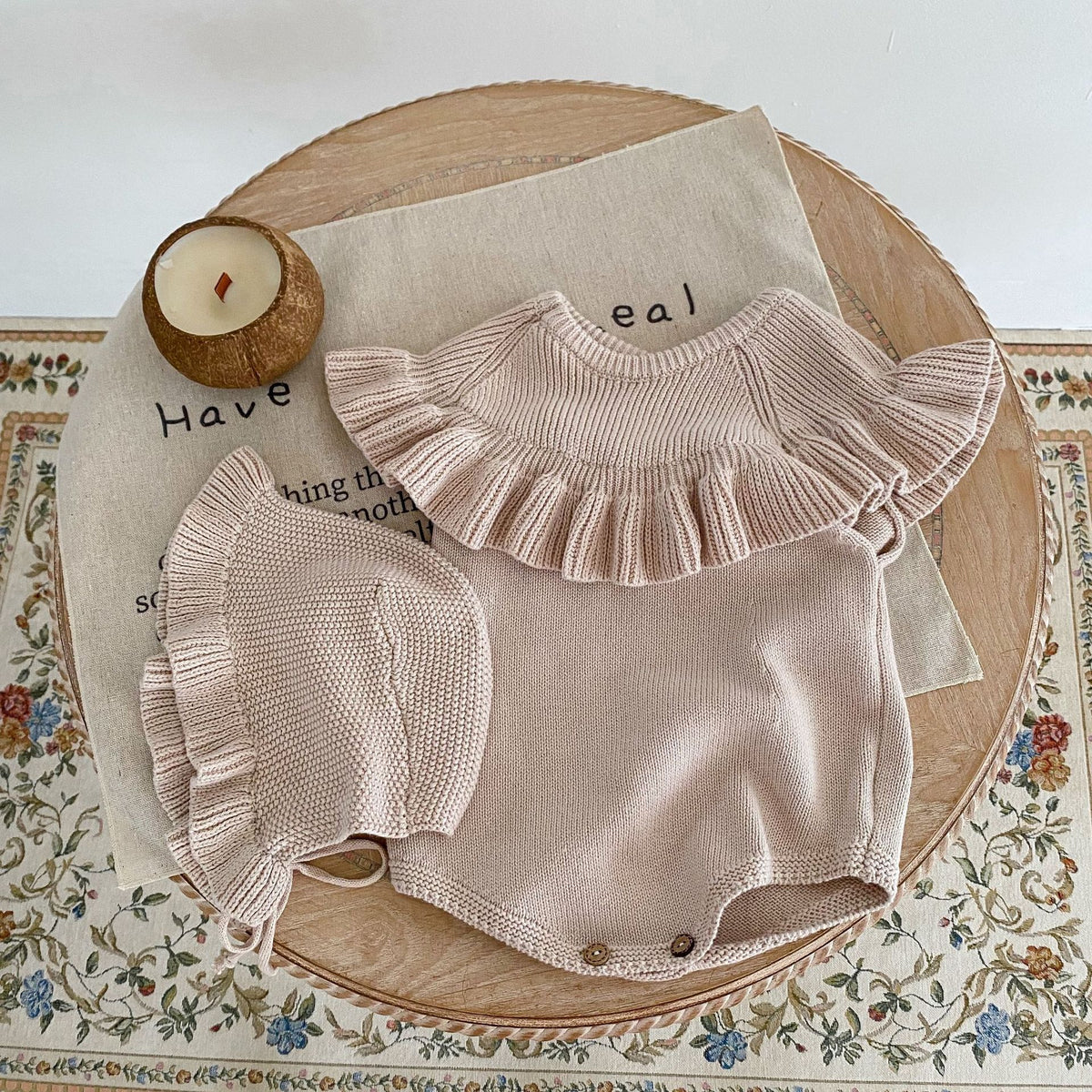 Oatmeal knit romper with ruffle collar on a round tray