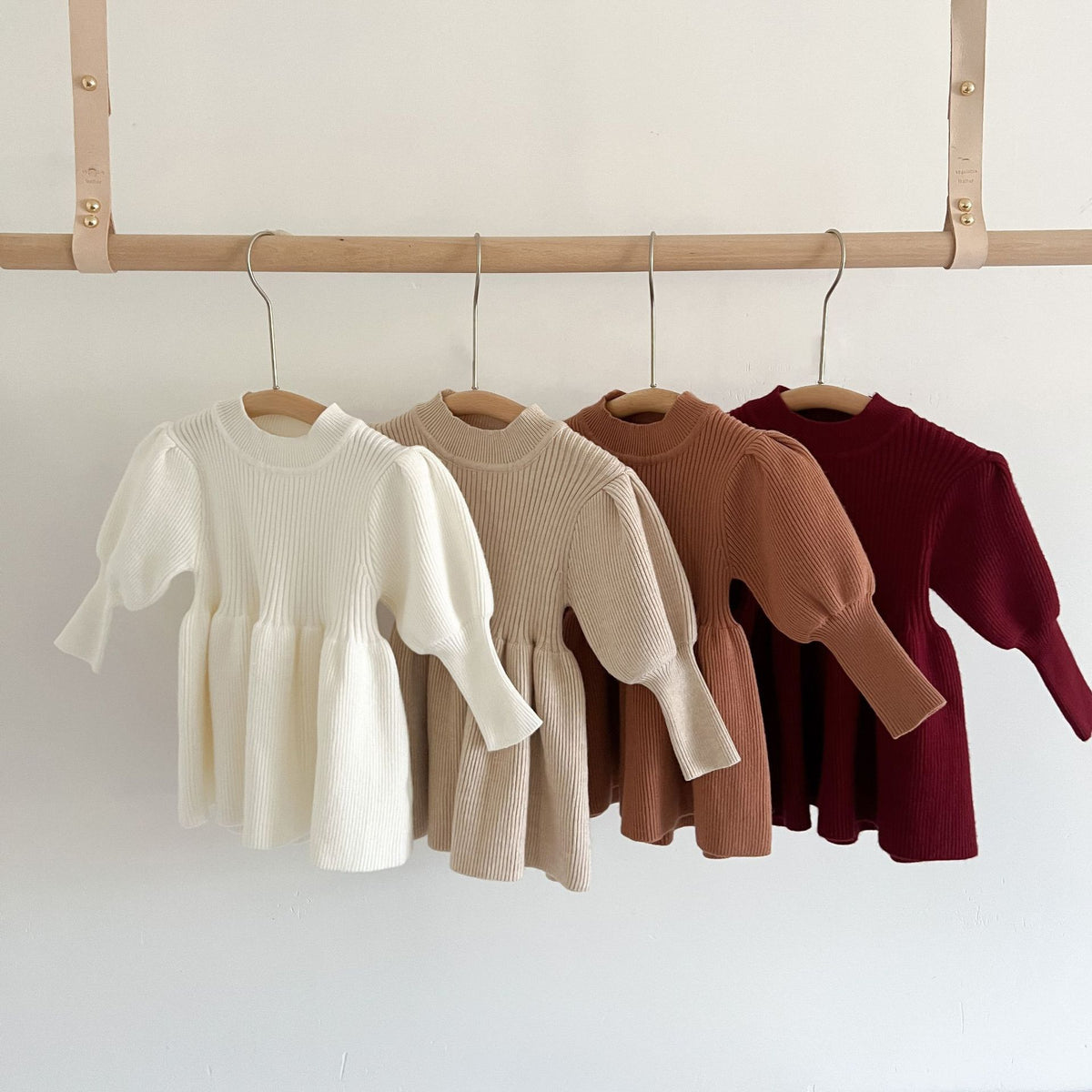 Four knit skater dresses hanging on a wooden rail