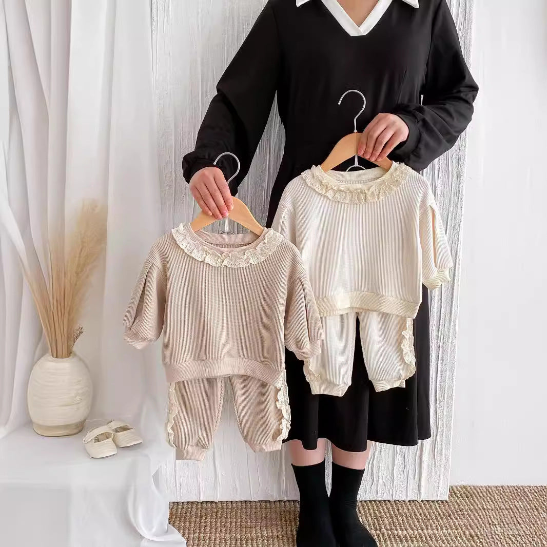 Beige and brown toddler sweater and jogger sets held on hangers