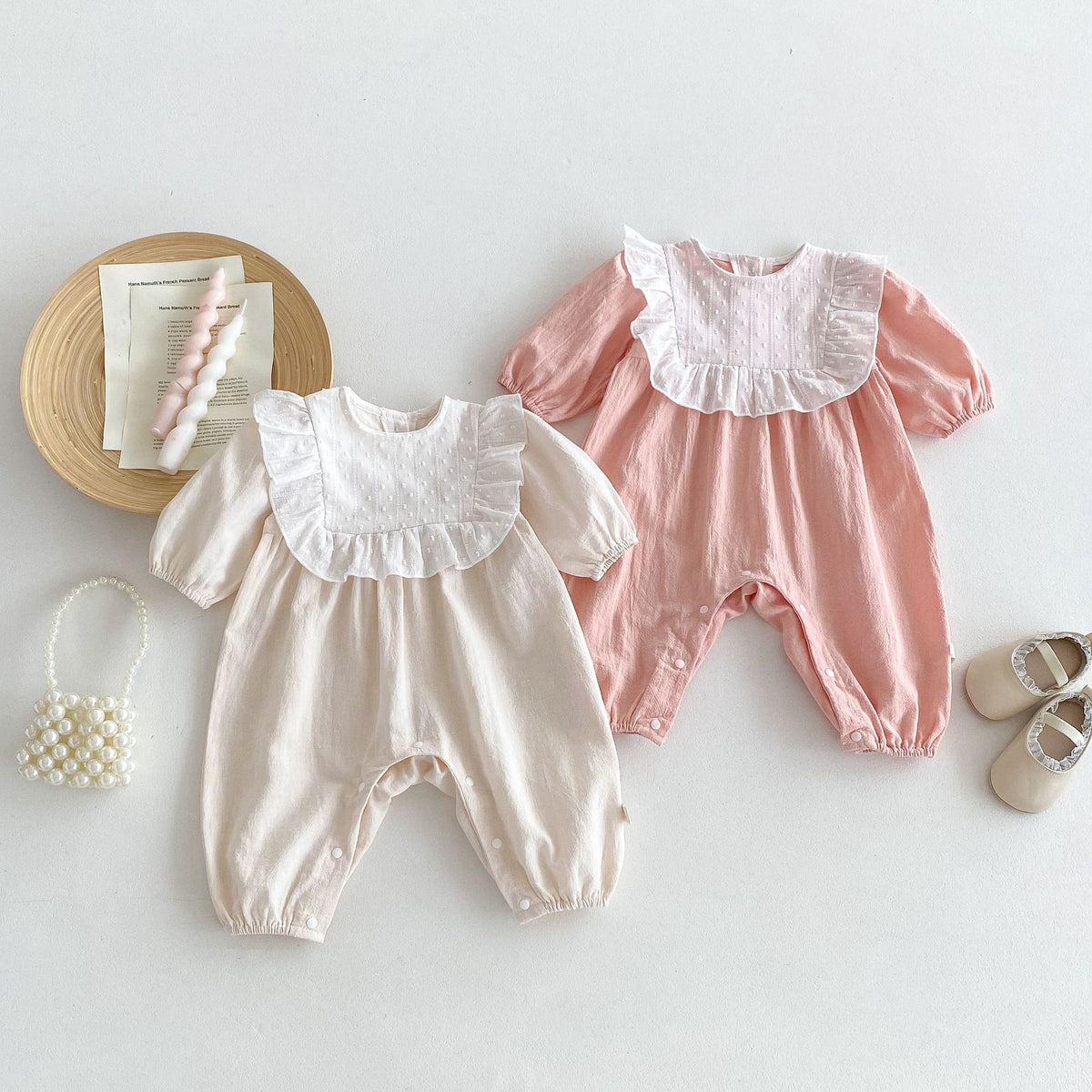 Beige and pink long sleeve baby rompers with lace collars, flat lay