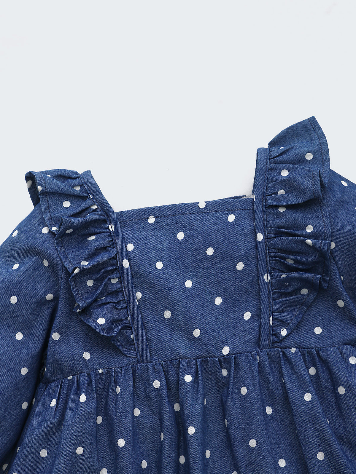 Close-up of ruffle shoulder on navy polka dot dress